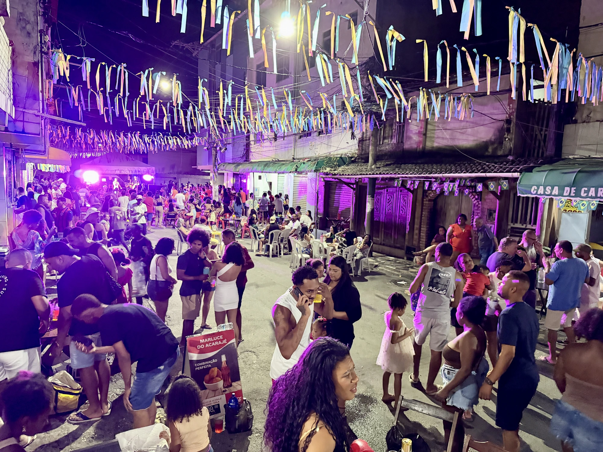 Rua de Pituaçu decorada com fitas coloridas, público em ritmo de festa, comércio local ativo — Adrielle Show Dia dos Pais 2026